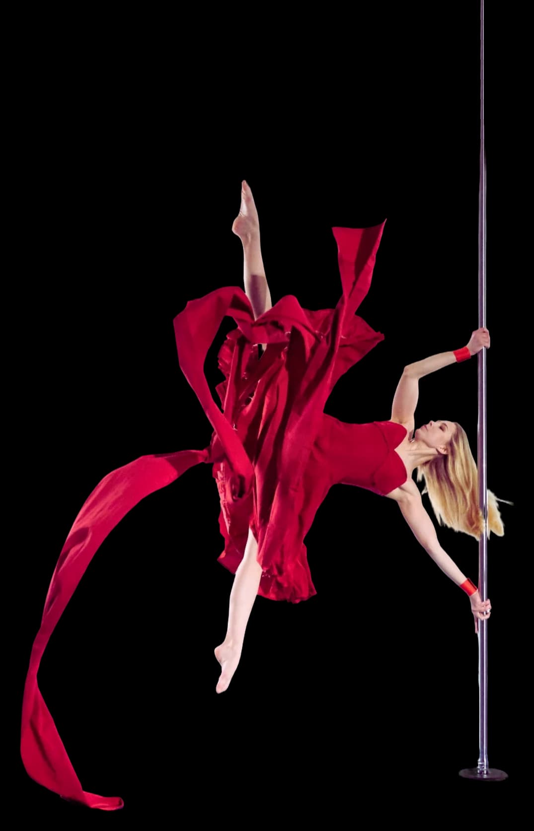 Pole dancer in a flowing red dress, holding a pole in a split