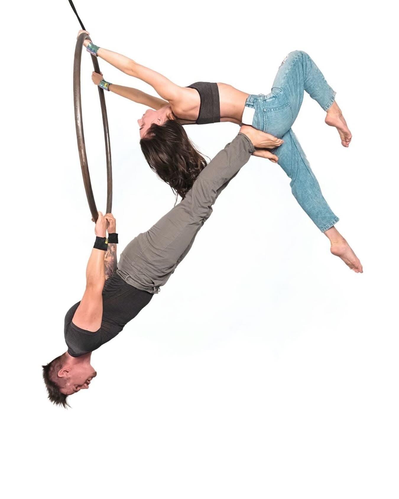 Two aerialists performing a duo pose on an aerial hoop, both wearing SneakyDeez wrist wraps