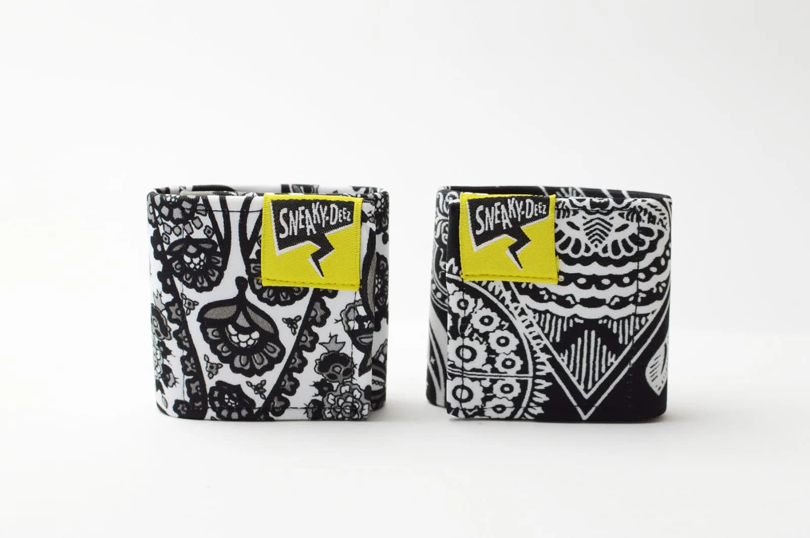 A pair of black and white paisley-print SneakyDeez wrist wraps on a white background